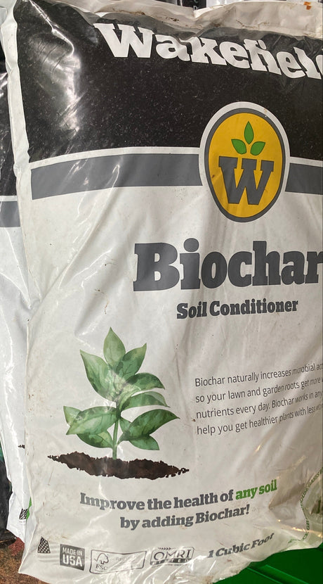 Bag of Wakefield Biochar Soil Conditioner on a surface with a green container in the background.