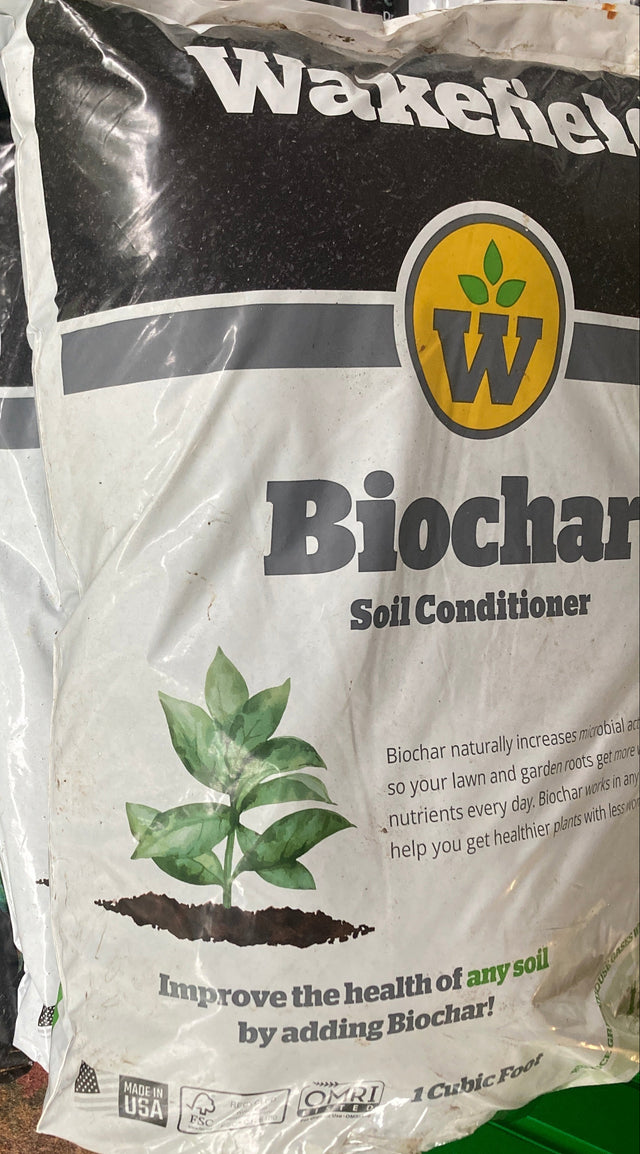 Bag of Wakefield Biochar Soil Conditioner on a surface with a green container in the background.